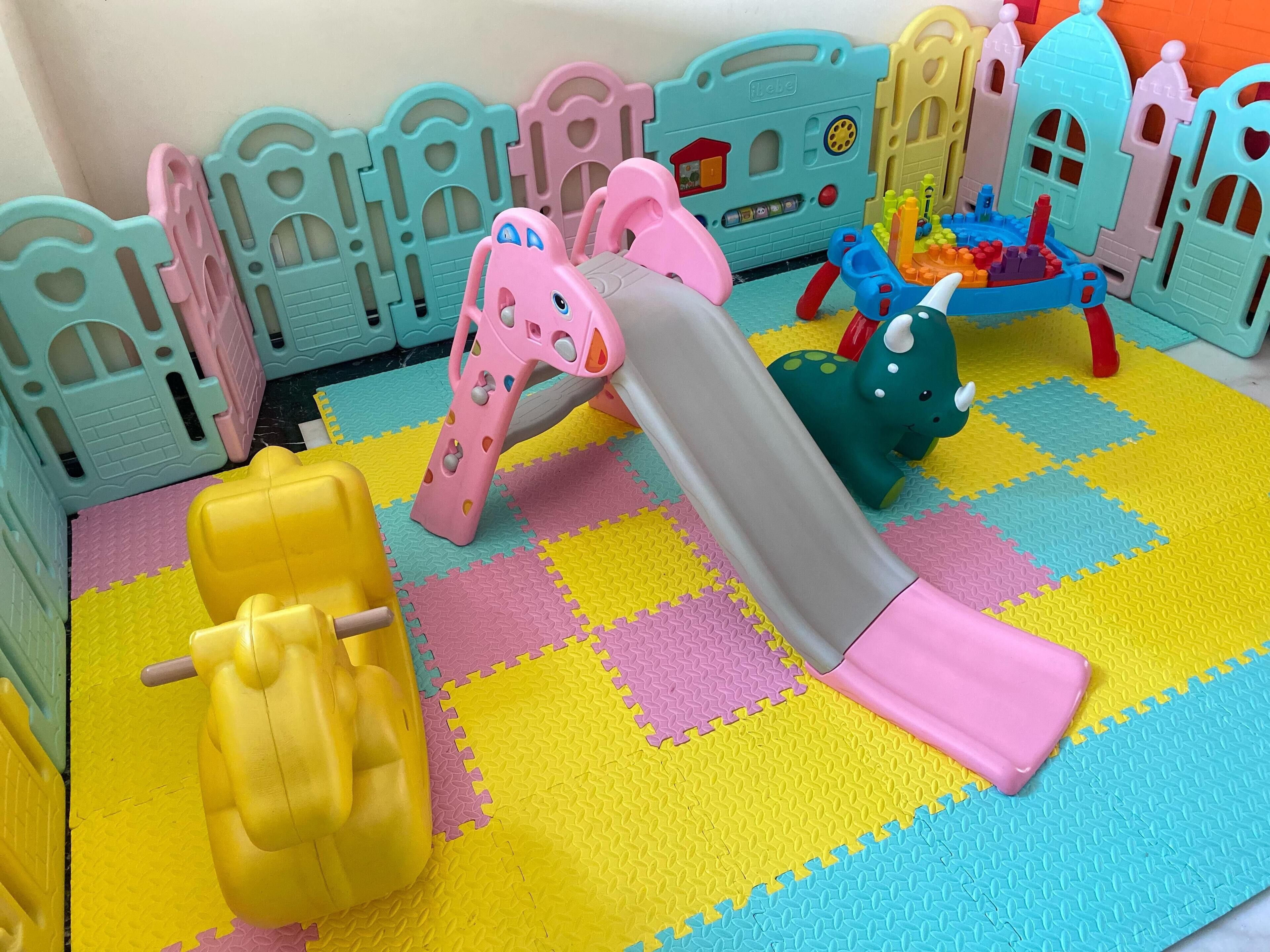 Un área de juegos infantiles con tobogán, estructuras para escalar y una pequeña casita con forma de castillo.