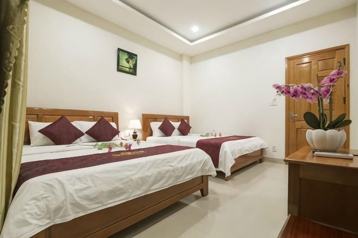 A hotel room with two beds, a desk, a door, and a wall-mounted picture.