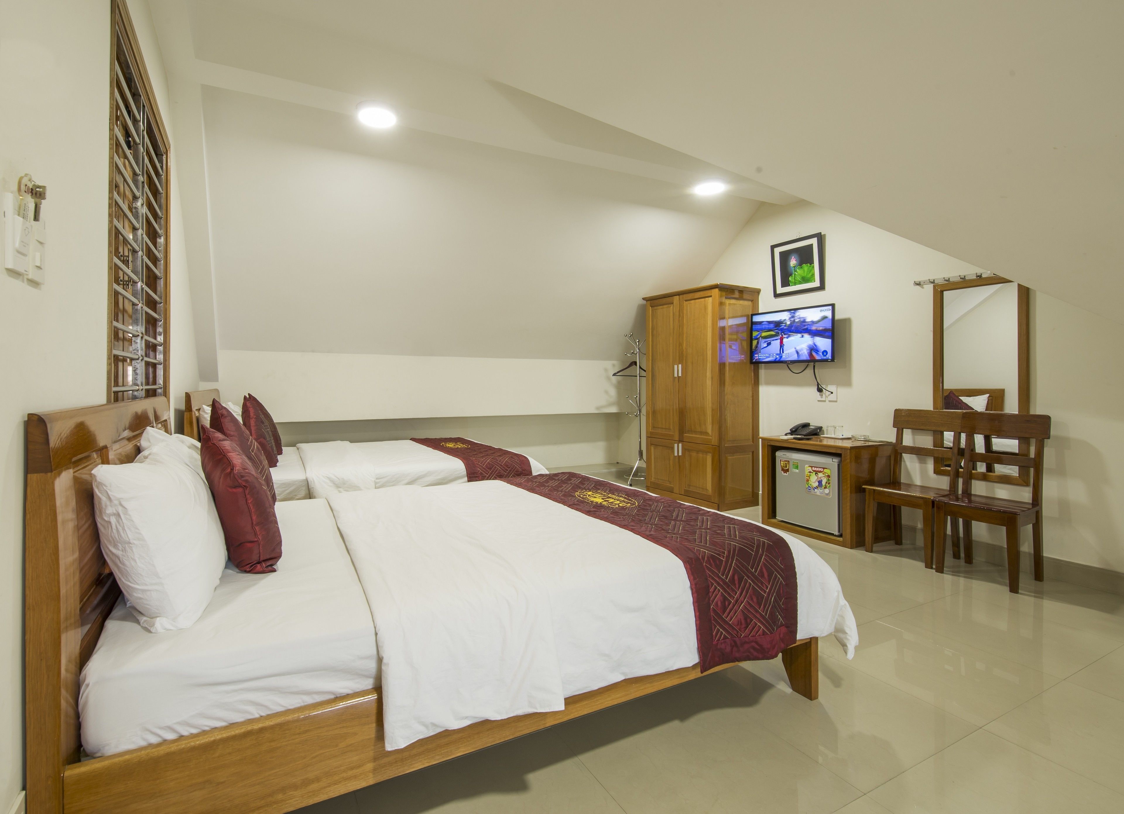 Una camera da letto con un letto, un armadio in legno, una scrivania, una sedia e un televisore appeso al muro.