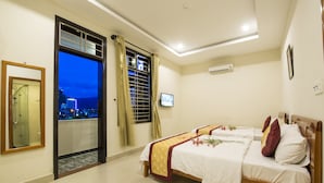 A hotel room with a balcony, a TV, and a bed with white bedding and decorative pillows. - Dam Tien Hotel (Da Nang)
