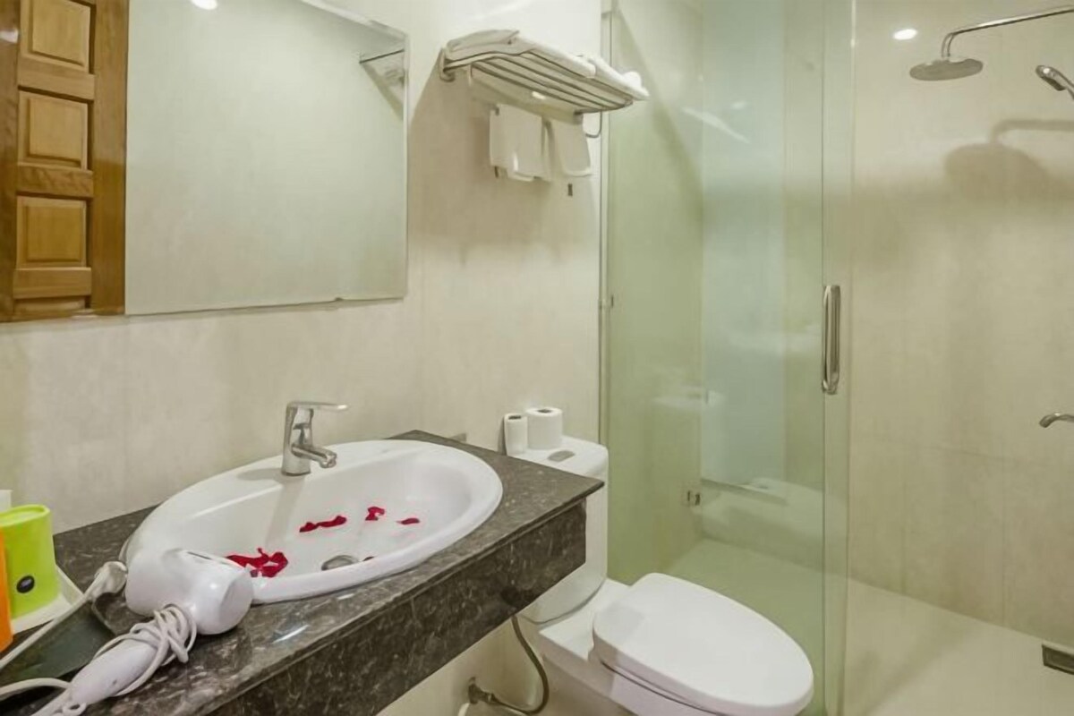 A bathroom with a sink, mirror, toilet, and shower.
