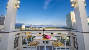A balcony with a table and chairs, overlooking a cityscape with buildings and mountains. - Dam Tien Hotel (Da Nang)