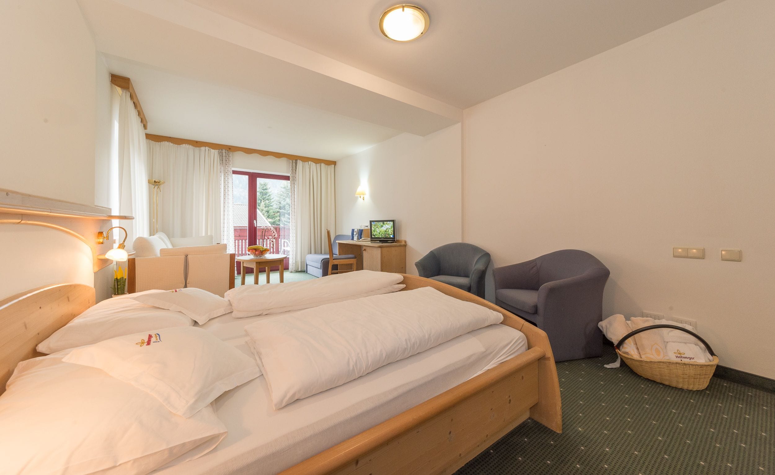 A hotel room with a bed, a desk, a chair, and a television.