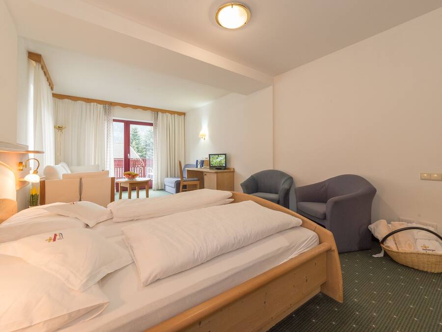 A hotel room with a bed, a desk, a chair, and a television.