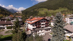 Ein mehrstöckiges Gebäude mit Balkonen, eingebettet in eine gebirgige Landschaft unter blauem Himmel.