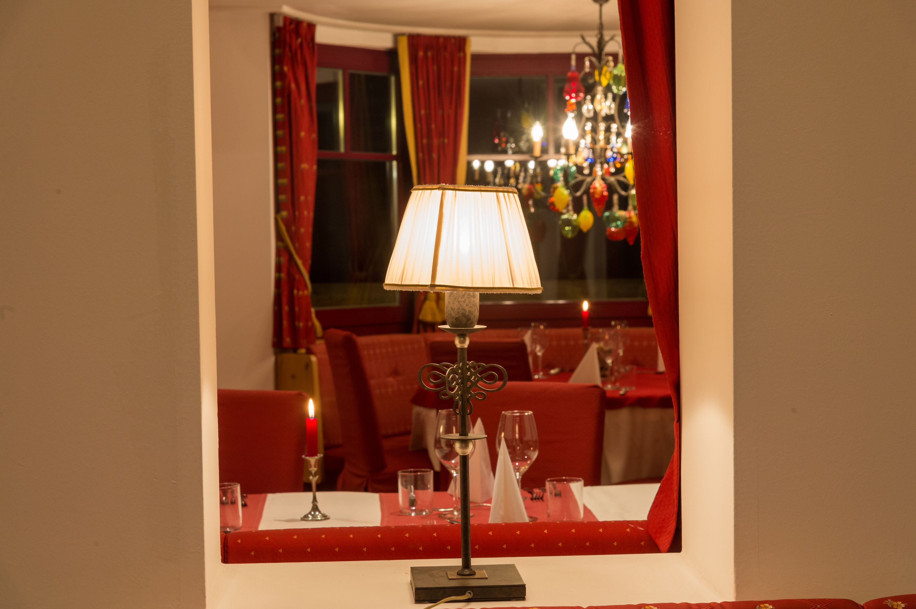 A dining area with a table set for two, a candle, and a decorative lamp.
