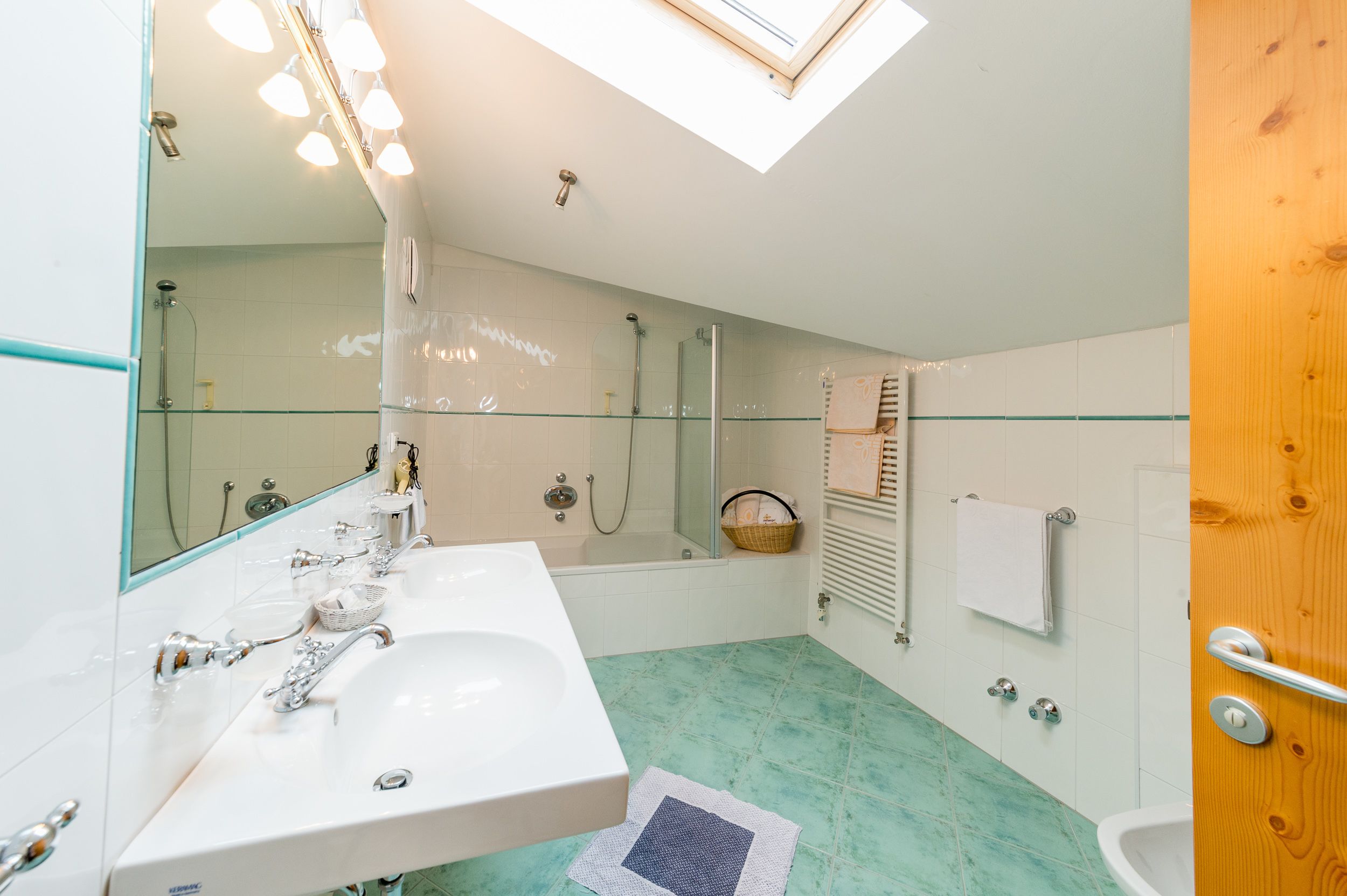 Un baño con cabina de ducha de vidrio, una bañera, un lavamanos blanco y una puerta de madera.