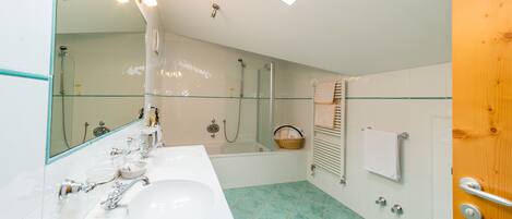 Un baño con cabina de ducha de vidrio, una bañera, un lavamanos blanco y una puerta de madera.
