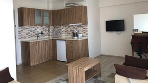 A modern kitchen with wooden cabinets, a dishwasher, and a tiled backsplash. - Dort Mevsim Suit Otel (Çanakkale)