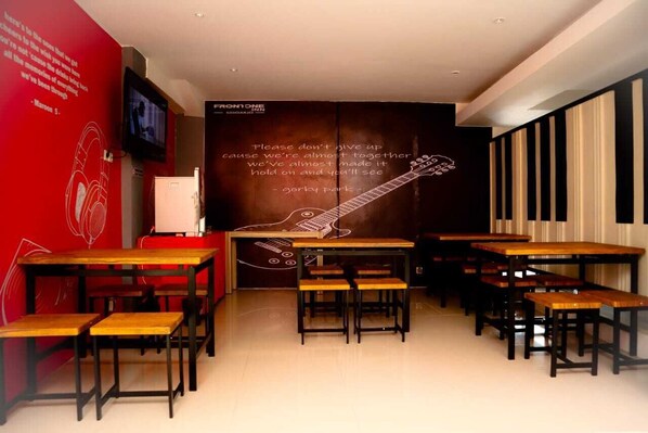 A restaurant with wooden tables and benches, a red wall with a quote, and a guitar mural.