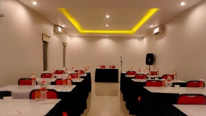 Un salón de conferencias con mesas y sillas, equipado con botellas de agua y un altavoz.