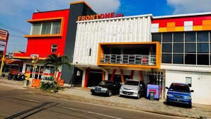 Un edificio con fachada roja y blanca, un letrero que dice Frontone Inn y varios coches estacionados.