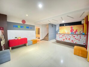 A reception area with a red table, a blue sofa, and a colorful counter. - Front One Inn Sidoarjo (Sidoarjo)