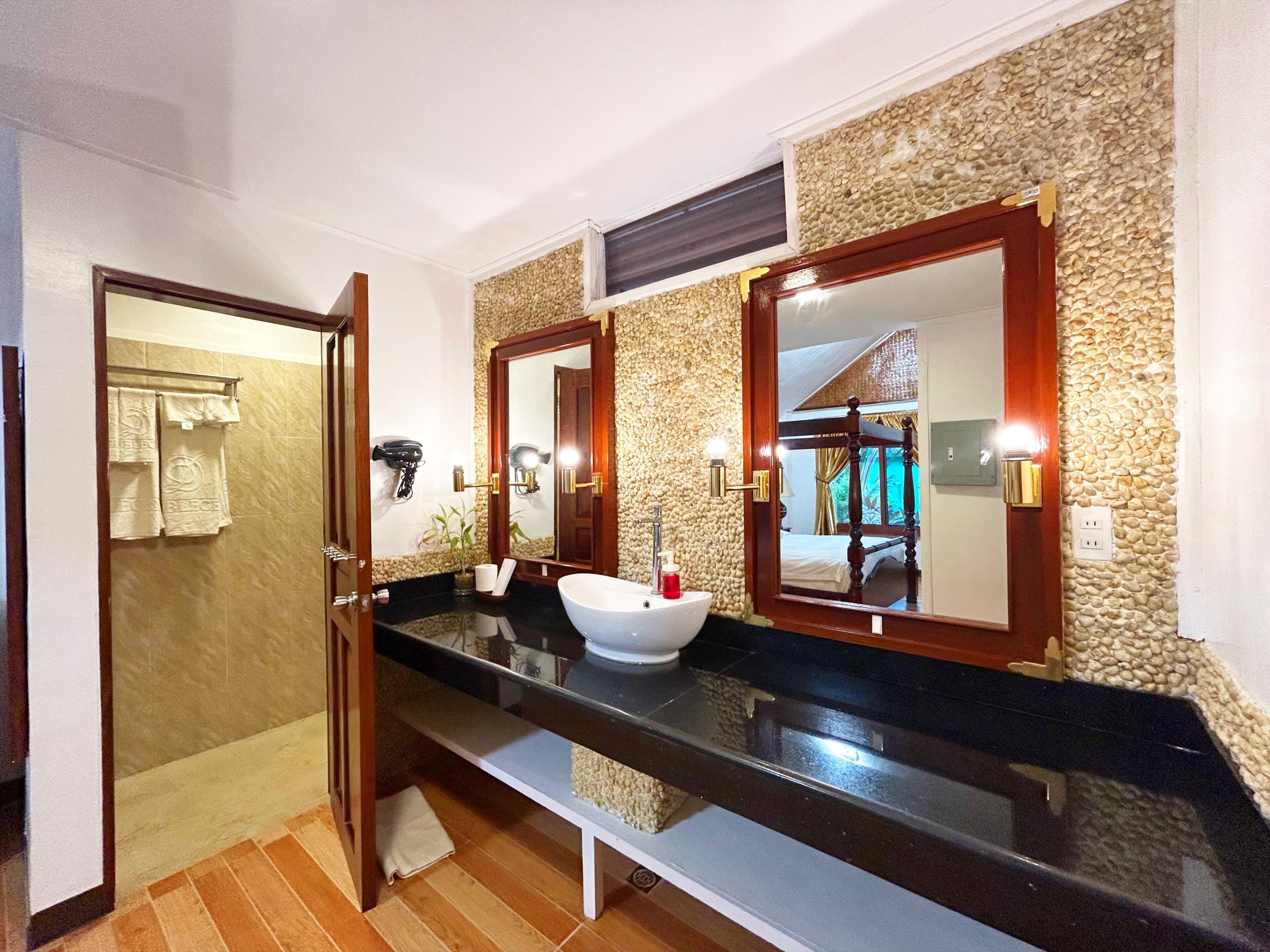 A bathroom with a black countertop, a white sink, and a mirror with a wooden frame.