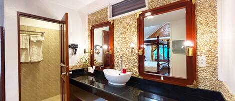 Un baño con encimera negra, lavabo blanco y espejo con marco de madera.