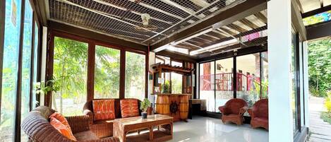 A spacious room with large windows, wicker furniture, and a ceiling with a grid pattern.
