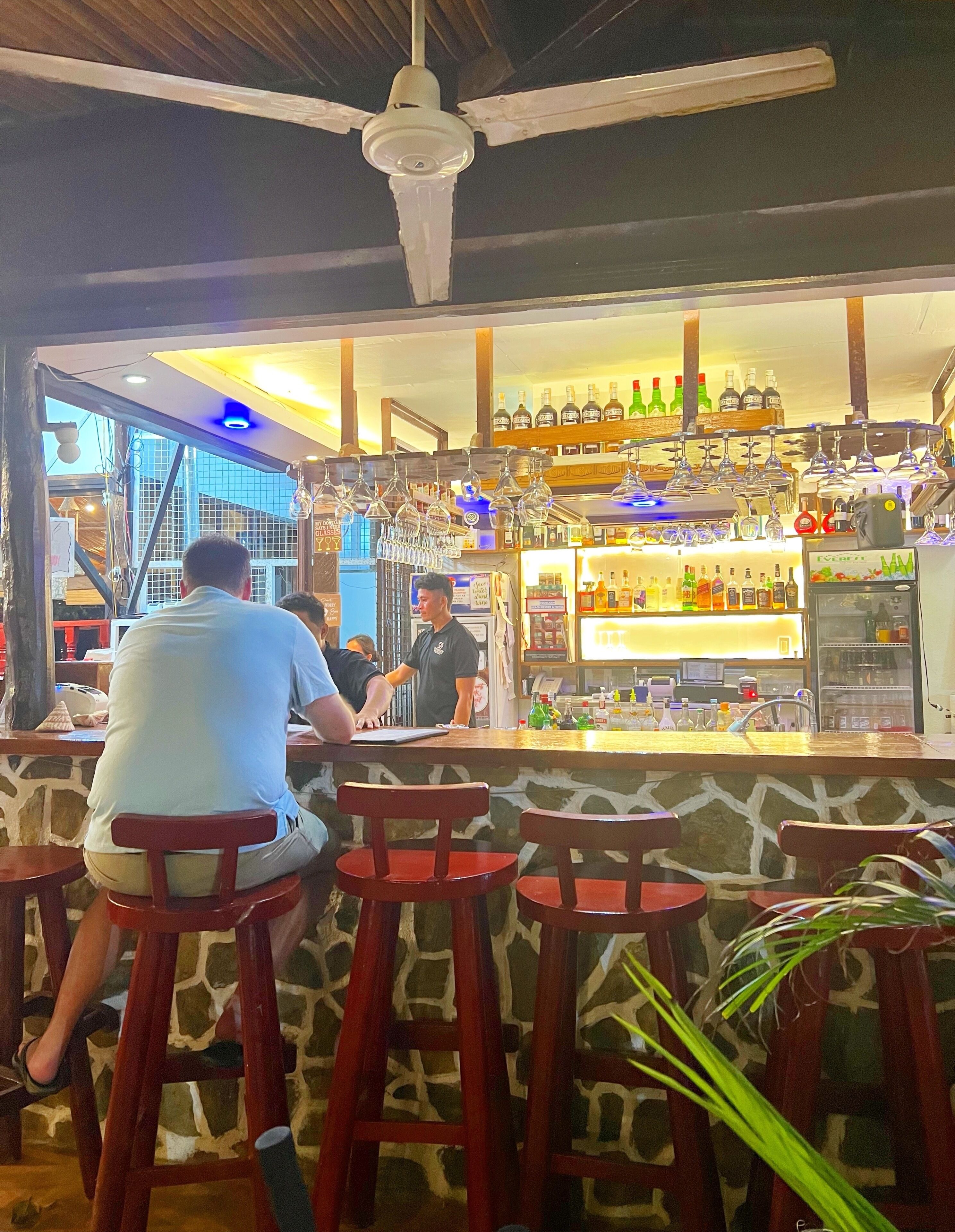 A bar area with stools, a counter, and a ceiling fan.