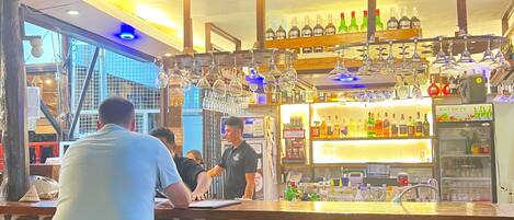 A bar area with stools, a counter, and a ceiling fan.