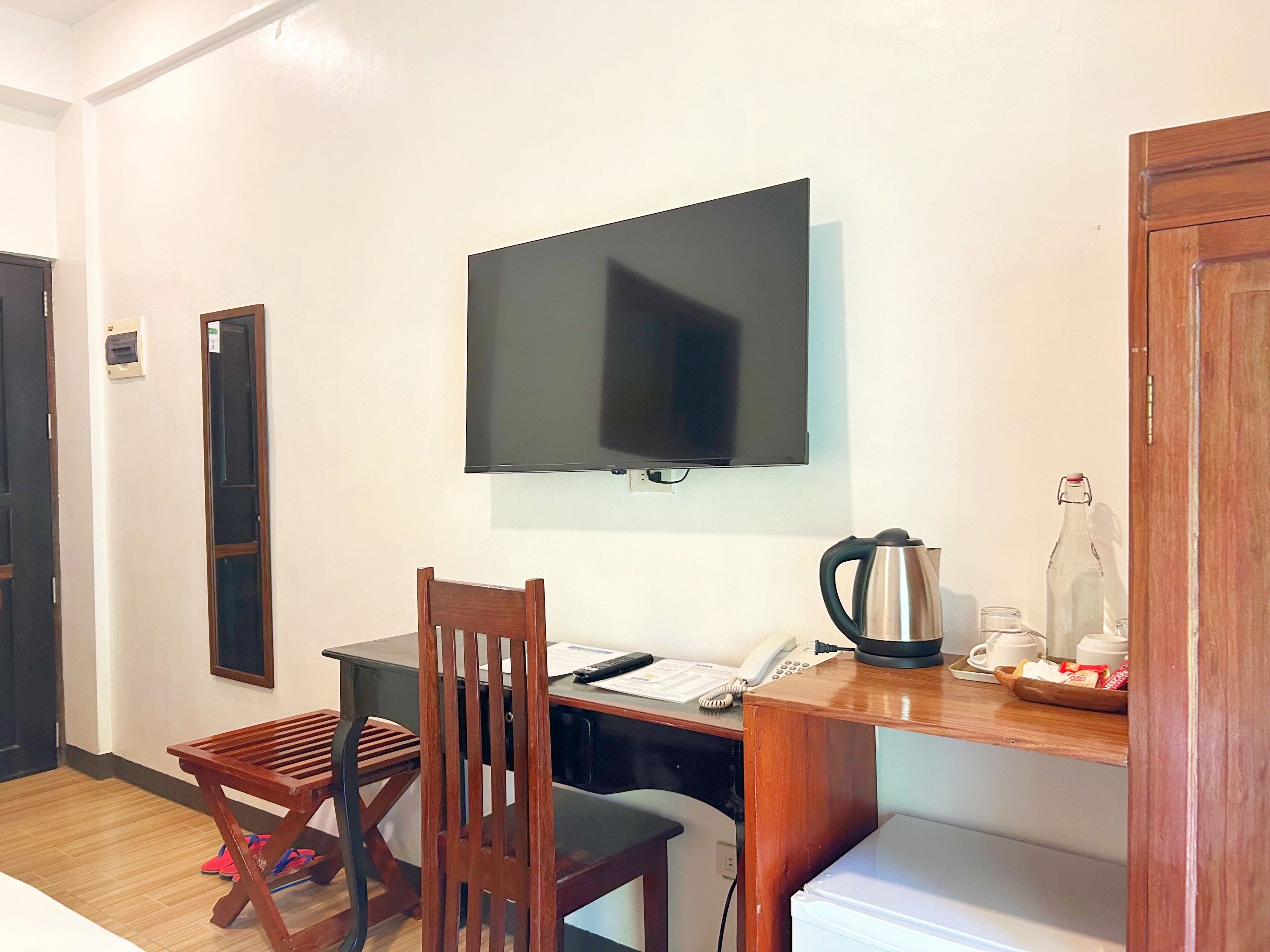 A small room with a desk, chair, television, and a coffee station.