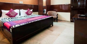 Une chambre d’hôtel avec un lit, une chaise, un bureau et une armoire.