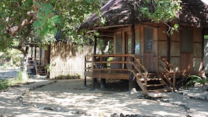 A traditional thatched-roof hut with a wooden porch and steps leading to the entrance. - Cashew Grove Beach Resort (Busuanga)