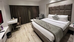 Una habitación de hotel moderna con una cama grande, un escritorio, una silla, un televisor y un ventilador de techo.