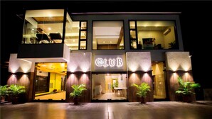 Un edificio moderno con un letrero que dice 'CLUB', ventanas amplias y plantas en macetas en la entrada.