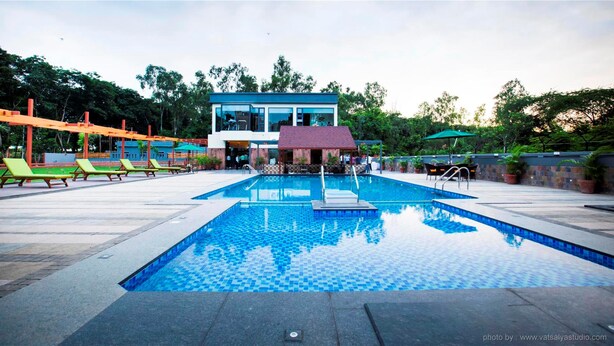 Una piscina con un diseño de baldosas a cuadros, rodeada de sillas de descanso y una zona de estar cubierta.