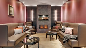 A modern lounge with leather sofas, a fireplace, and a framed artwork on the wall.