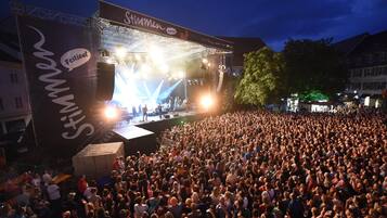 Un escenario de conciertos grande al aire libre con una multitud de personas frente a él.