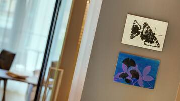 Two artworks on a wall, one depicting a butterfly and the other featuring flowers.