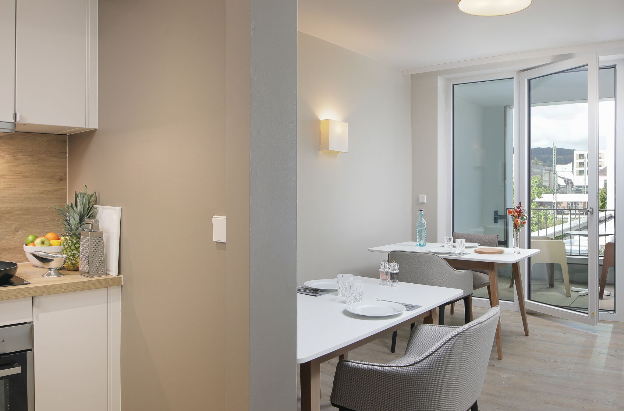 A modern kitchen with a dining area, a large window, and a view of the city.
