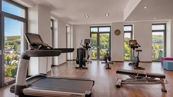 Un gimnasio moderno con diverso equipo de ejercicio, amplias ventanas que ofrecen vistas panorámicas y un espacio amplio.