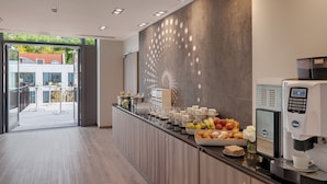 A modern kitchen area with a coffee station, including a coffee machine and a fruit display.