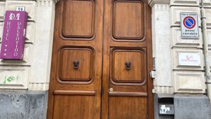 A large wooden double door with a classical architectural design, flanked by ornate stonework and a sign indicating the location as Hotel Valentino. - Hotel Valentino (Catania)