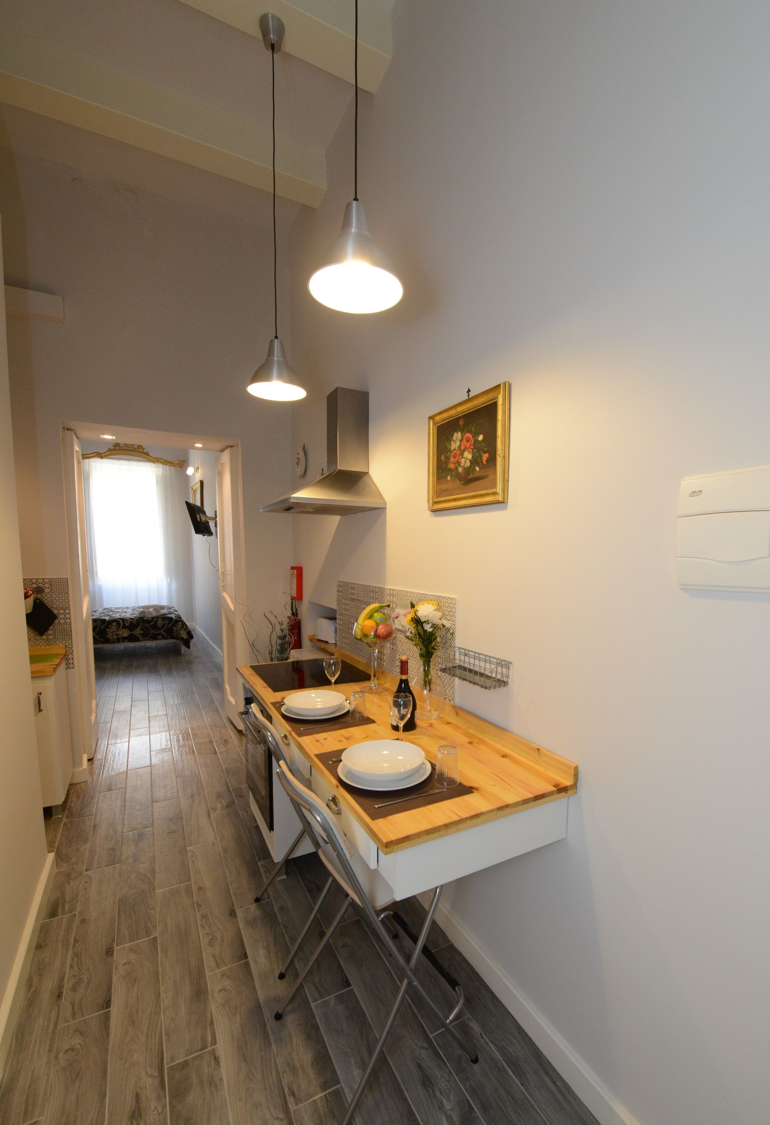A modern kitchen with a wooden countertop, two pendant lights, a sink, and a dining area.