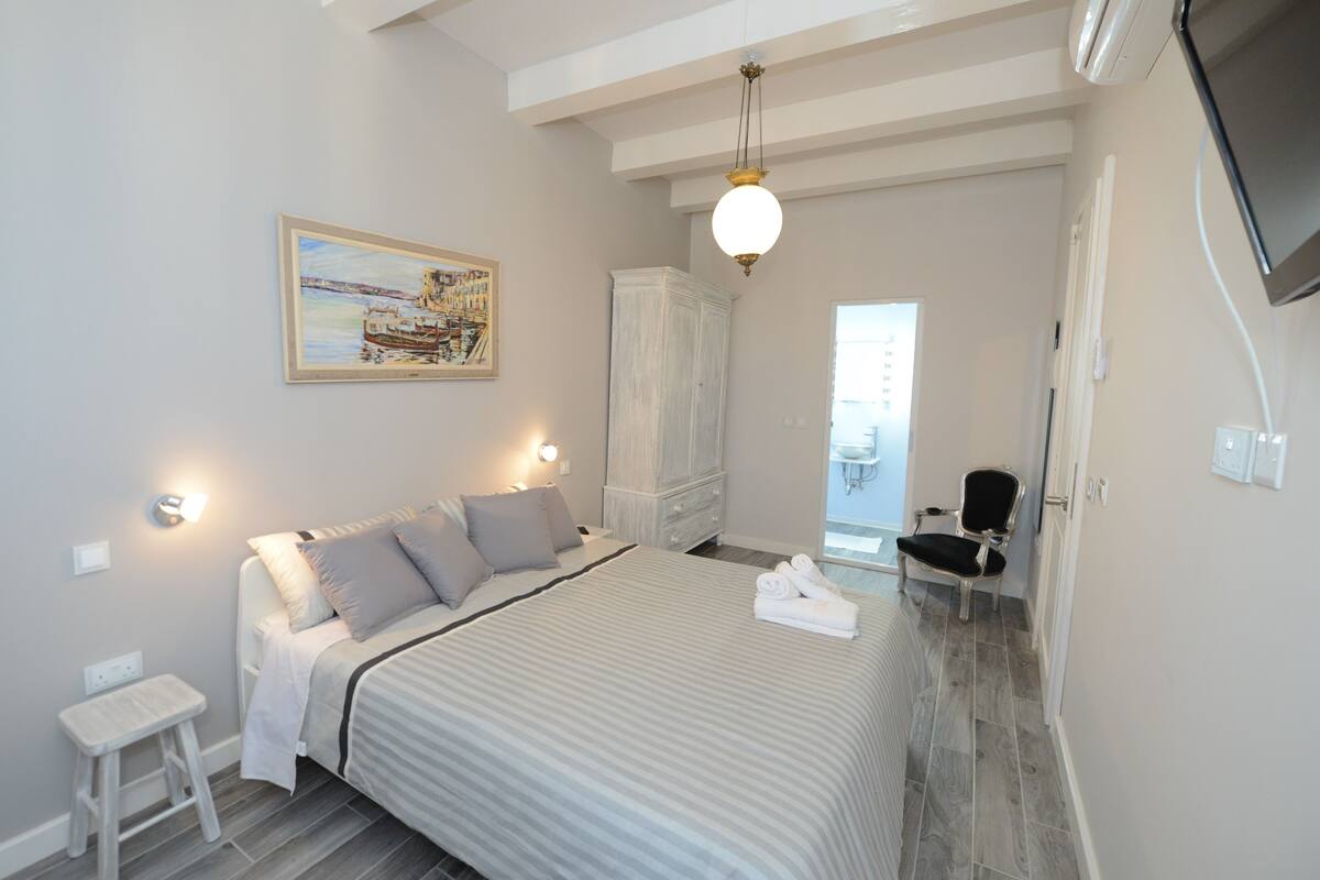 A bedroom with a bed, a nightstand, a wardrobe, a chair, and a painting on the wall.