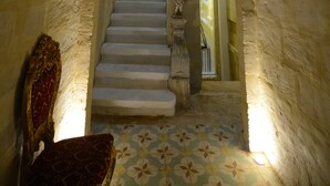 A grand staircase with a clock, framed pictures, and a patterned floor.