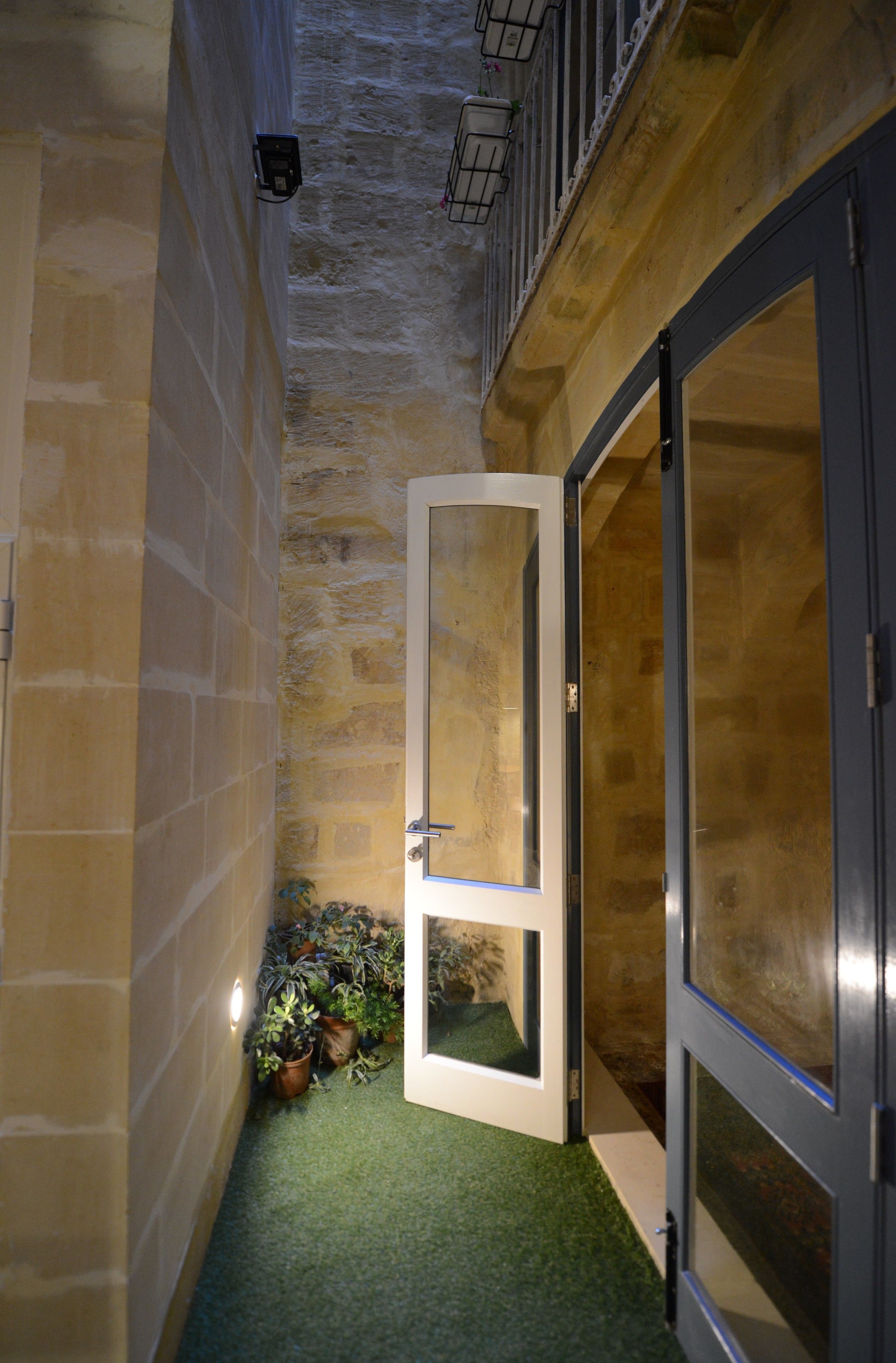 A narrow hallway with a door, potted plants, and a textured wall.