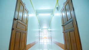 A corridor with wooden doors, a tiled floor, and fluorescent lighting. - Nadpob Mansion (Phunphin)