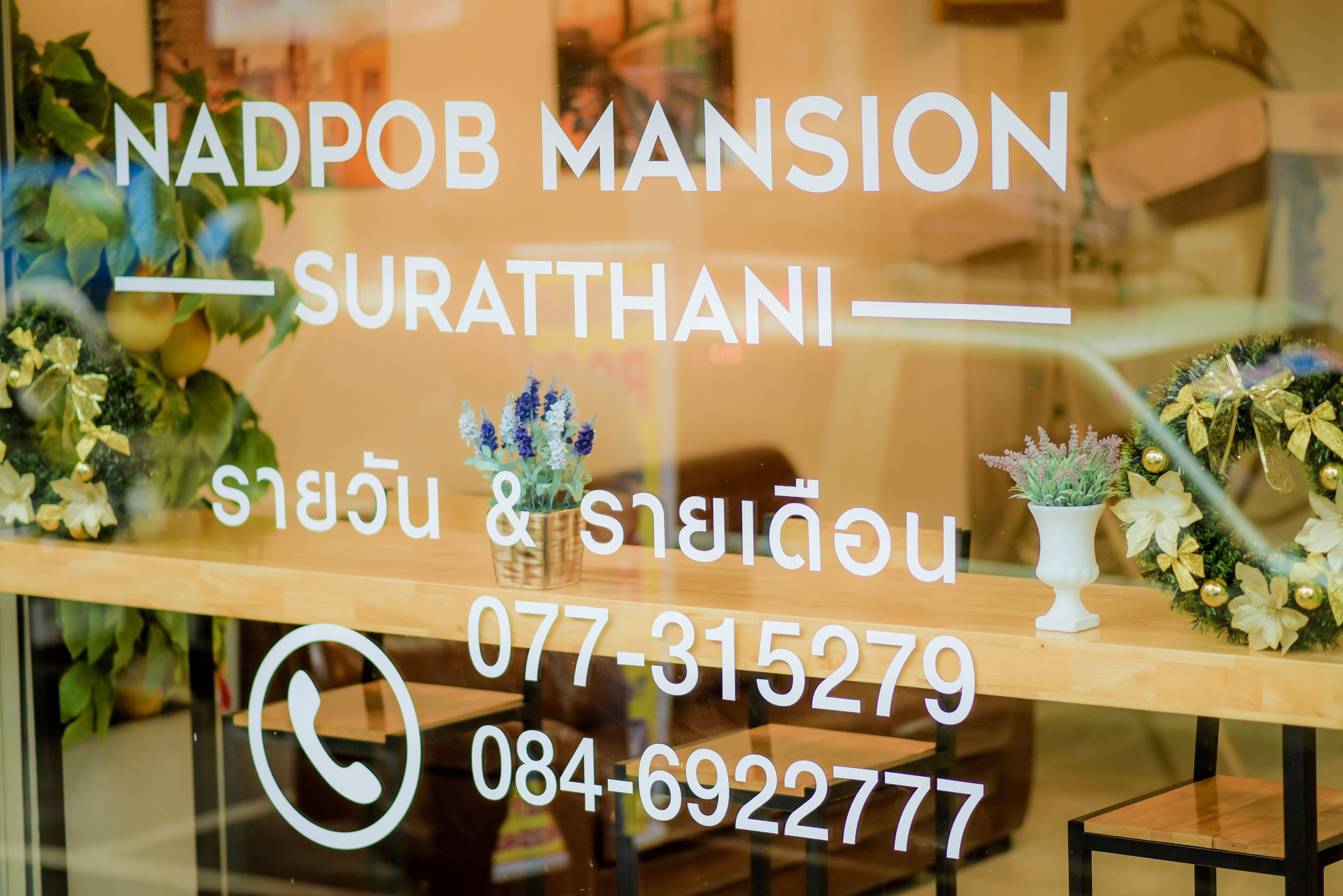 Hotellin kyltti, jossa lukee »NADPOB MANSION» ja on ilmoitettu yhteystiedot.