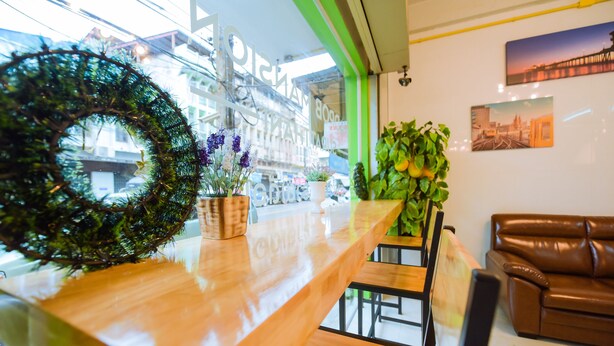 A reception area with a wooden counter, a green-framed window, and a brown leather couch. - Nadpob Mansion (Phunphin)