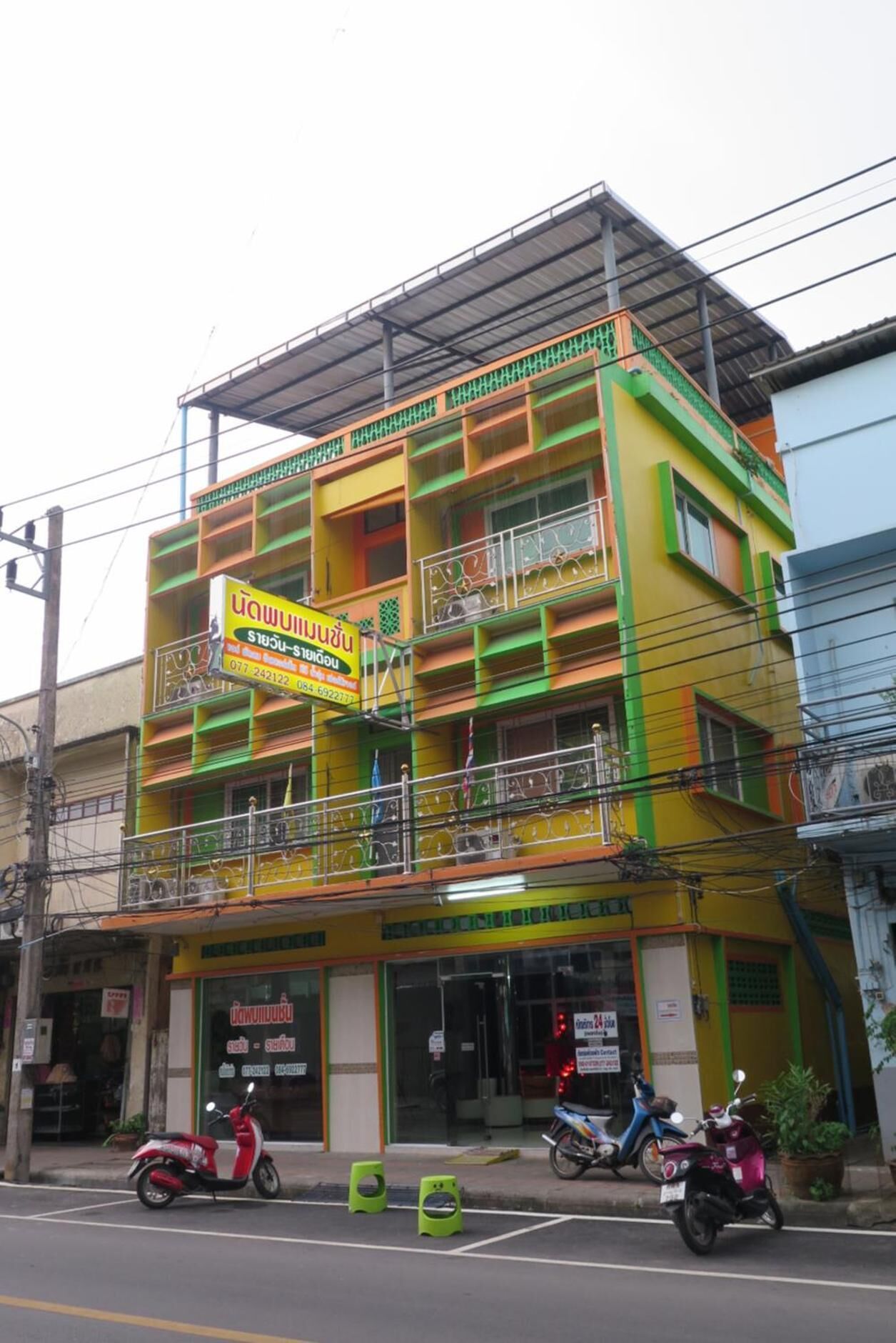 Un edificio de varios pisos con fachada colorida, con balcones y un letrero que indica un establecimiento comercial.