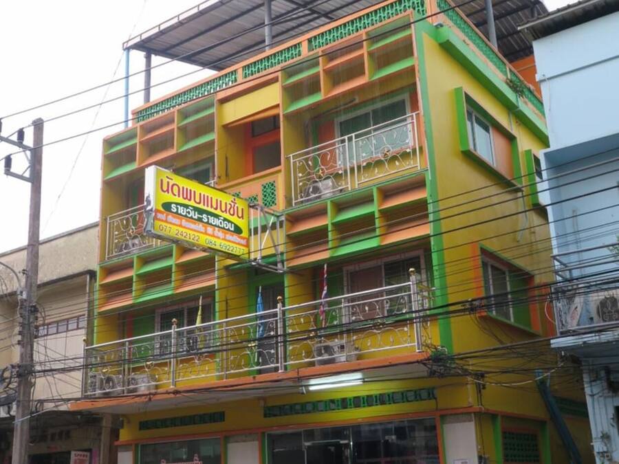 Un edificio de varios pisos con fachada colorida, con balcones y un letrero que indica un establecimiento comercial.