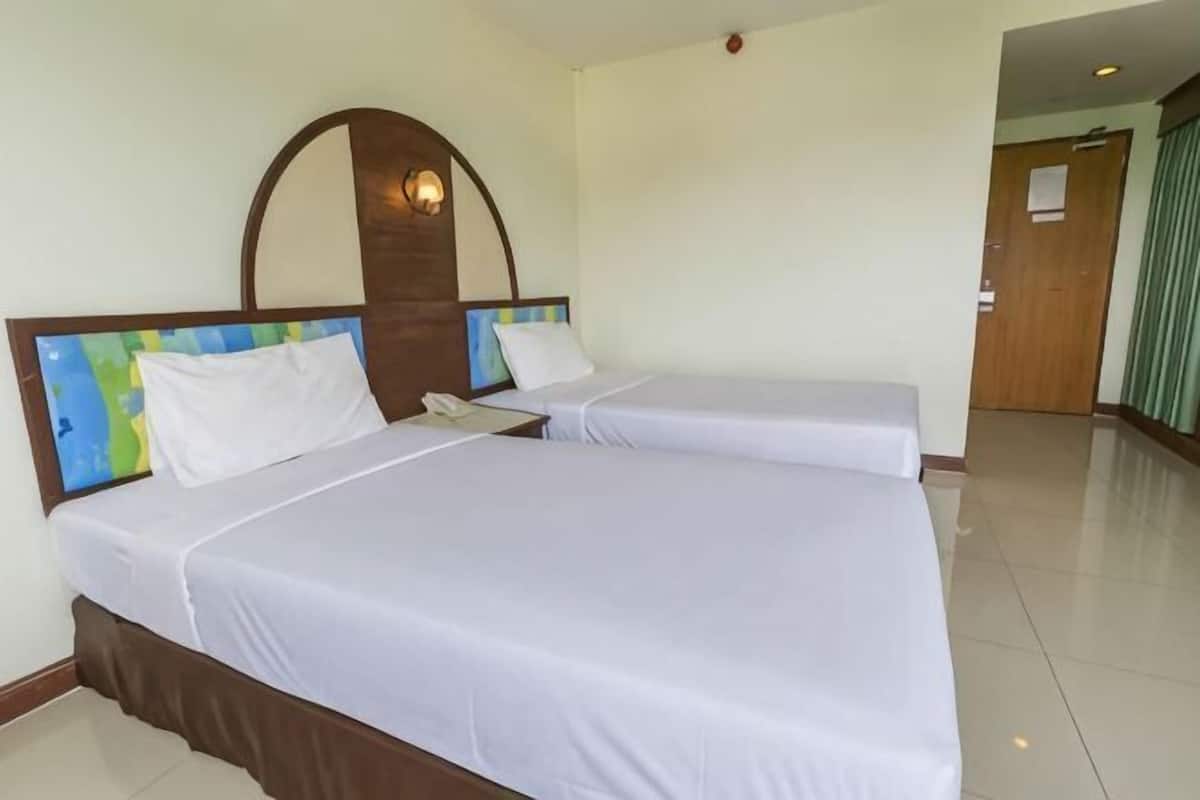 A hotel room with two beds, a wooden headboard, a telephone, and a door in the background.