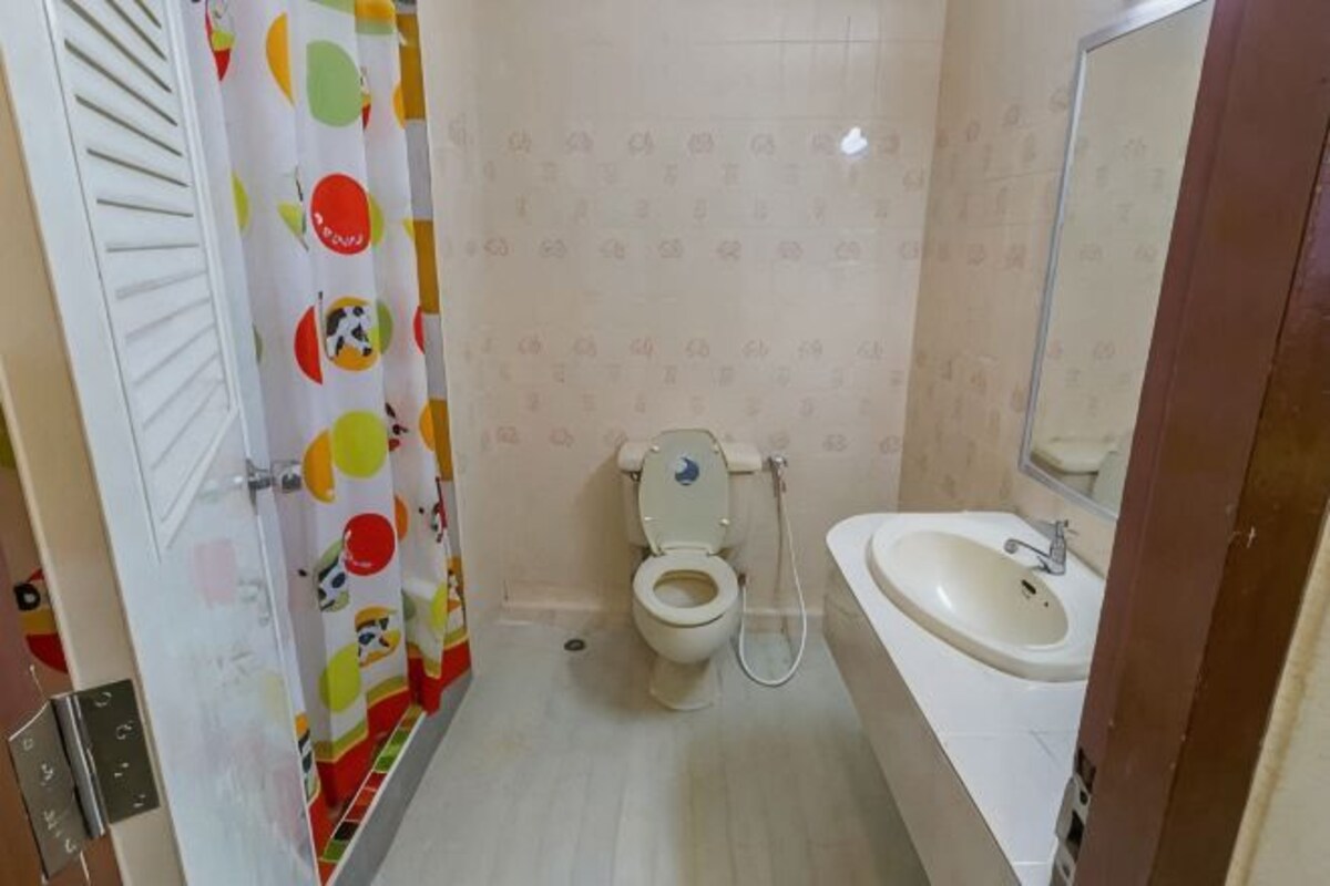 A bathroom with a toilet, sink, mirror, and a shower curtain with a cartoon character design.