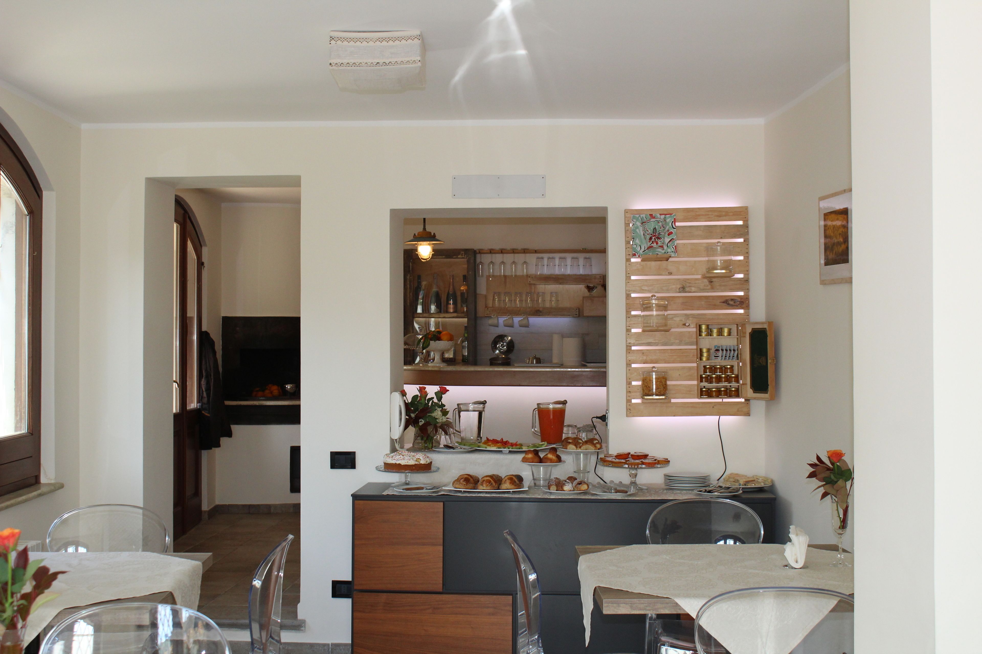 Una cocina moderna con una isla central, un área de comedor con sillas traslúcidas y una barra con estantes y una lámpara colgante.