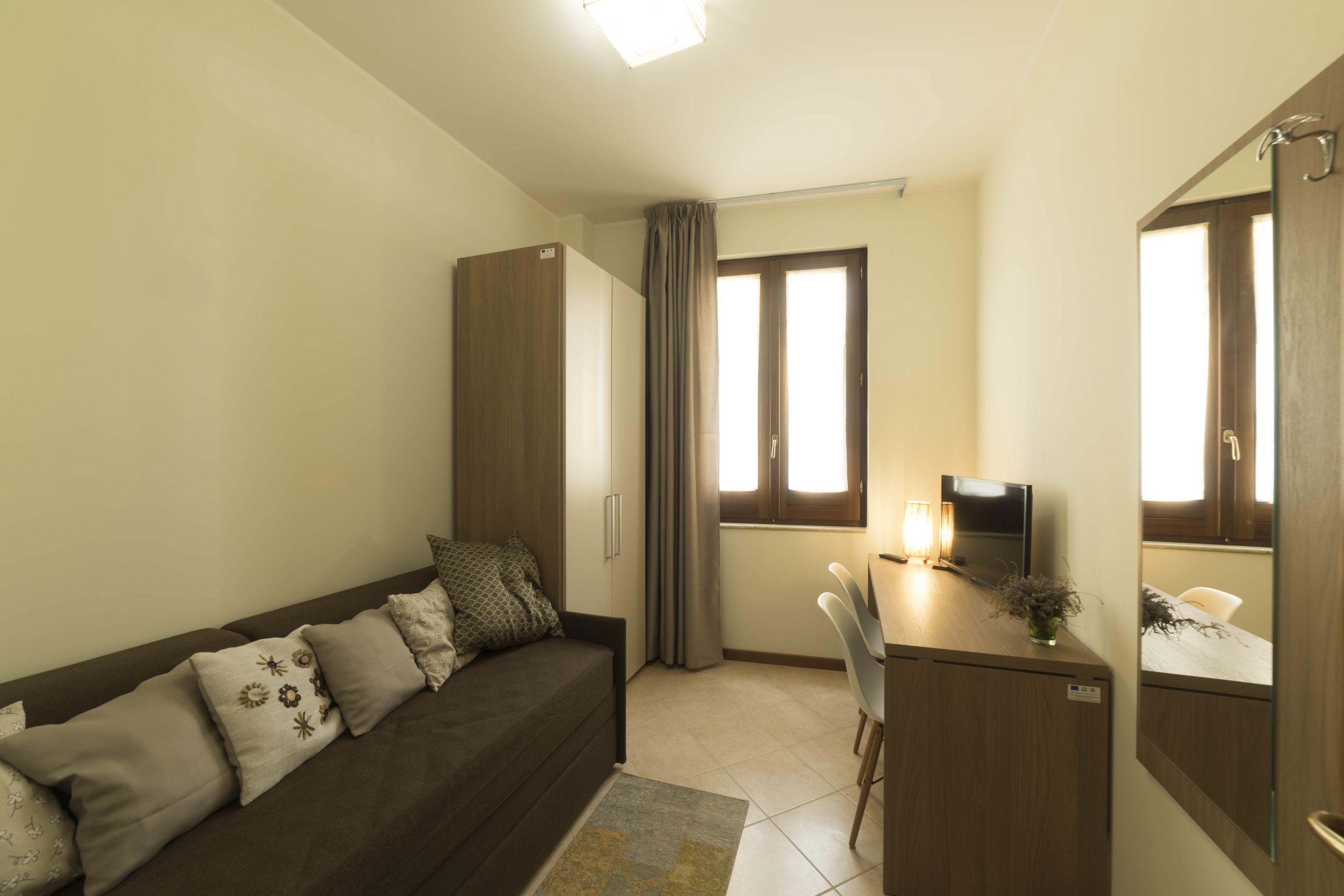 A compact living space with a sofa, a desk, a TV, and a wardrobe.