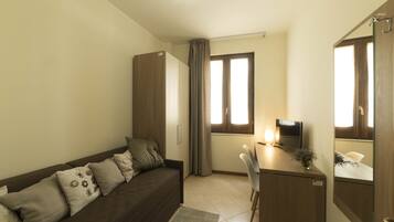 A compact living space with a sofa, a desk, a TV, and a wardrobe.