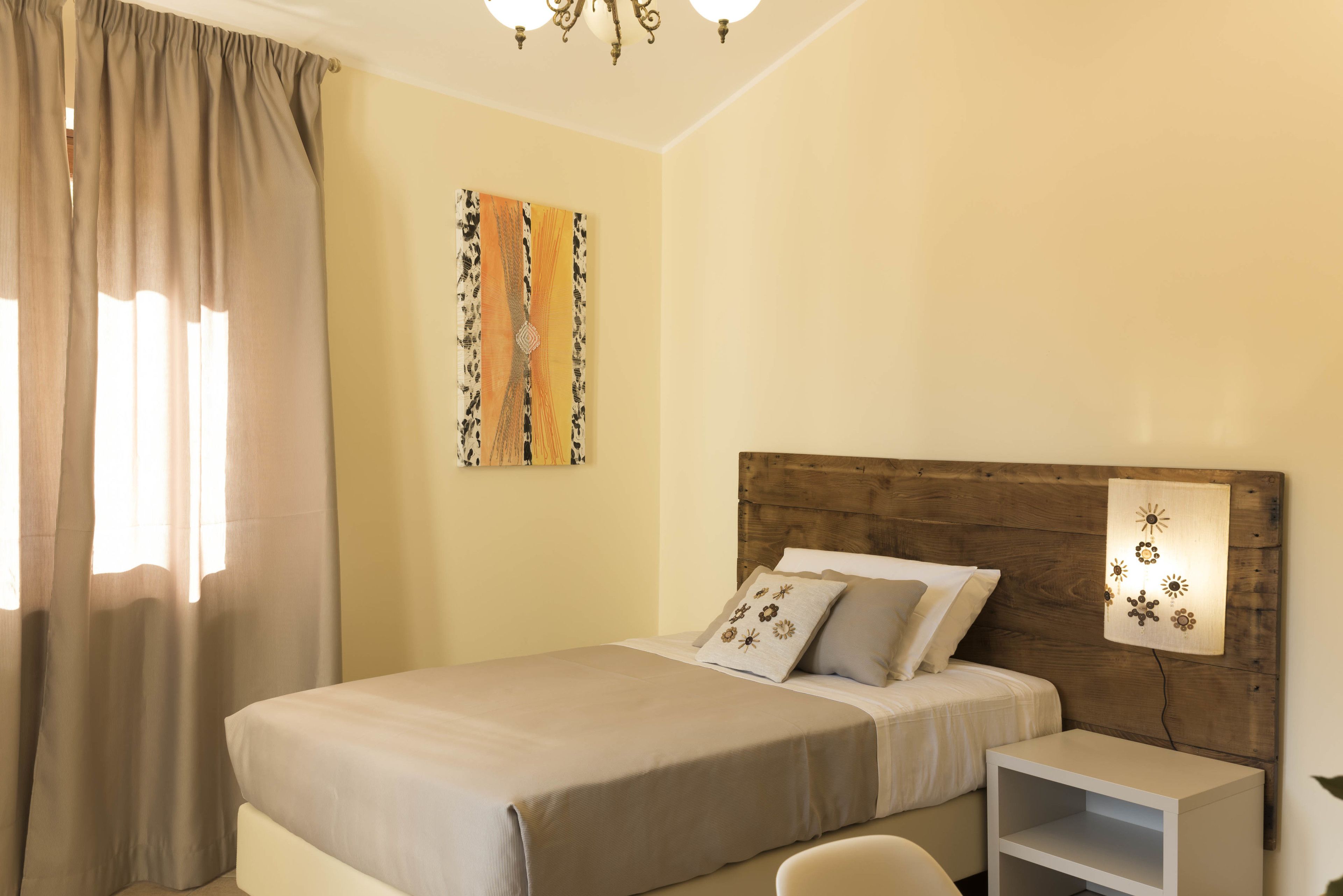 A neatly arranged bedroom with a bed, a bedside table, and a wall-mounted light fixture.